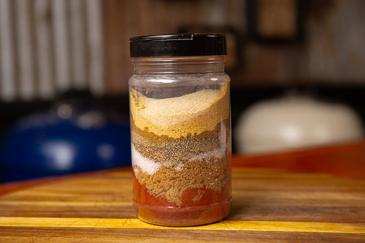 A jar with all the chicken rub ingredients layered in it