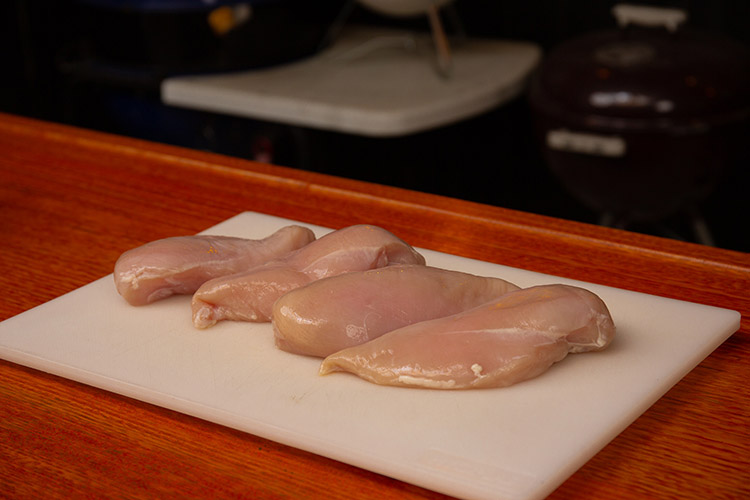 Raw chicken breasts on a chopping  white board