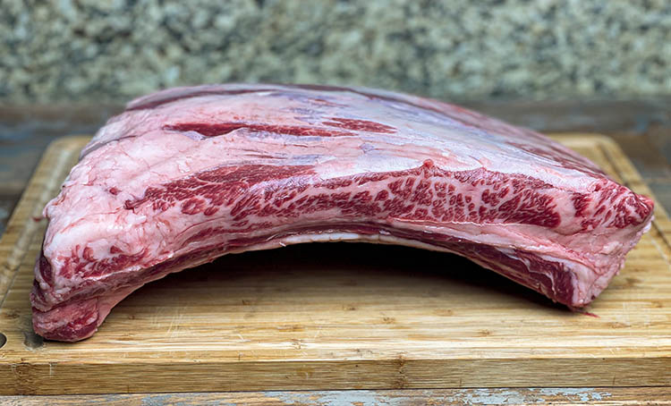 Side view of raw beef ribs showing streaks of marbling