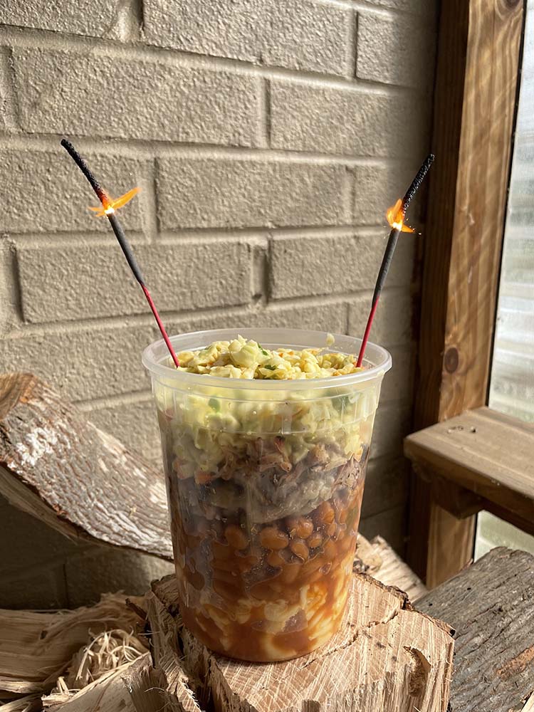 clear quart cup layered with mac, beans, pork, slaw with 2 lit sparklers 