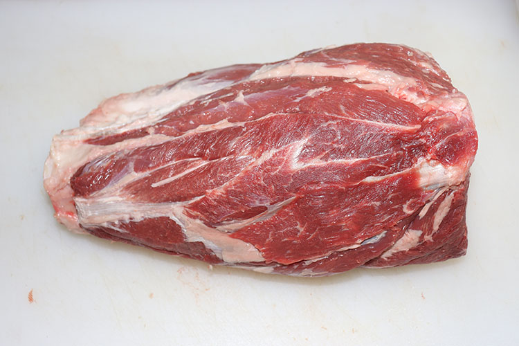 raw beef shank, trimmed on a white chopping board