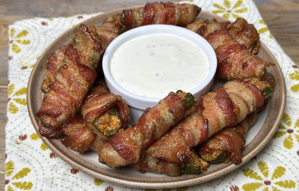 bowl of smoked jalapeños poppers on table with dipping sauce