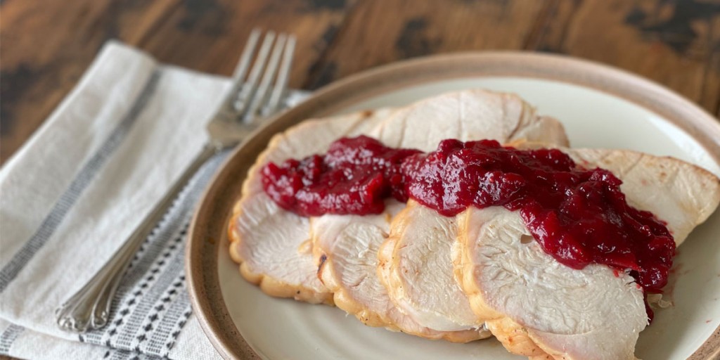 sliced turkey on a plate with cranberry sauce