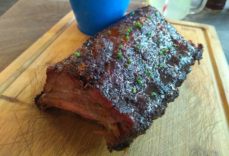 cooked half rack of baby back pork ribs on a wooden board