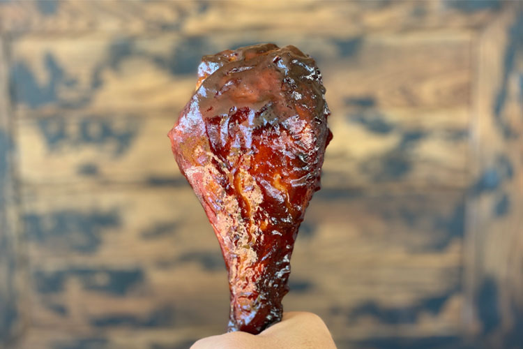 cooked, basted turkey leg being held upright by a hand