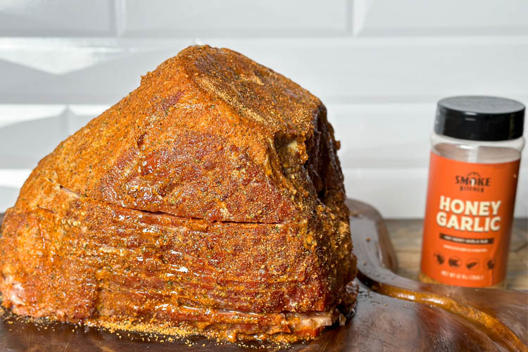 seasoned spiral ham with a jar of Smoke Kitchen Honey Garlic rub next to it