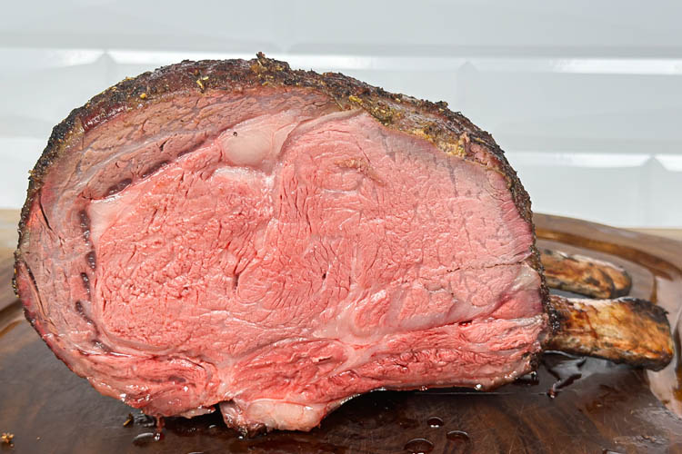 cooked prime rib cut in half on wooden board