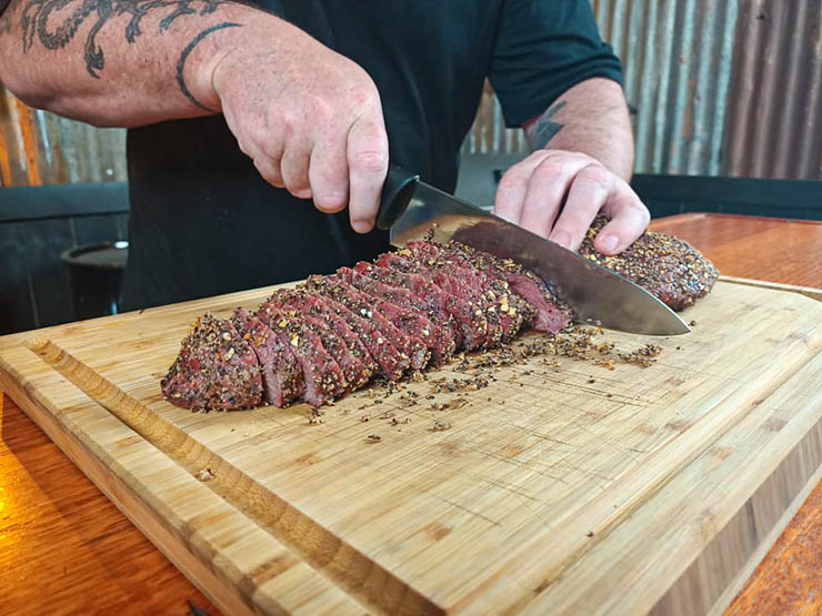 a man slicing cooked tri tip with a chefs knife
