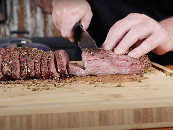 a man slicing a section of the tri tip with a knife
