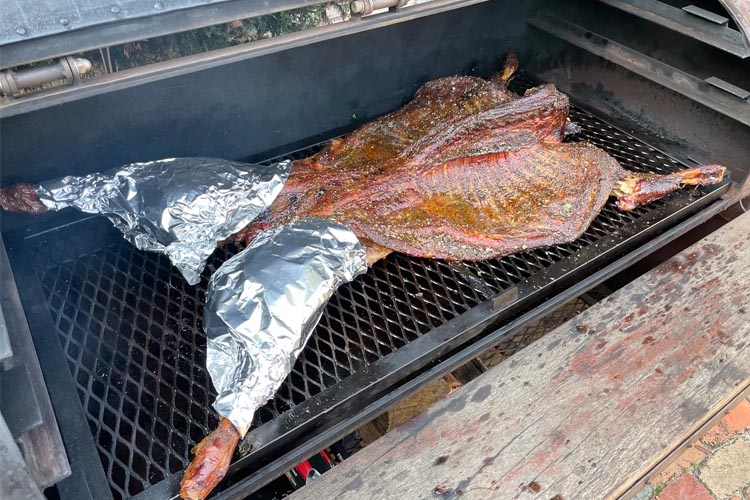 whole lamb on smoker with foil on hams