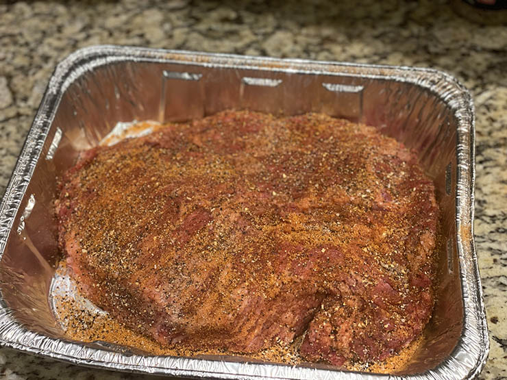 uncooked seasoned brisket point in a baking tray