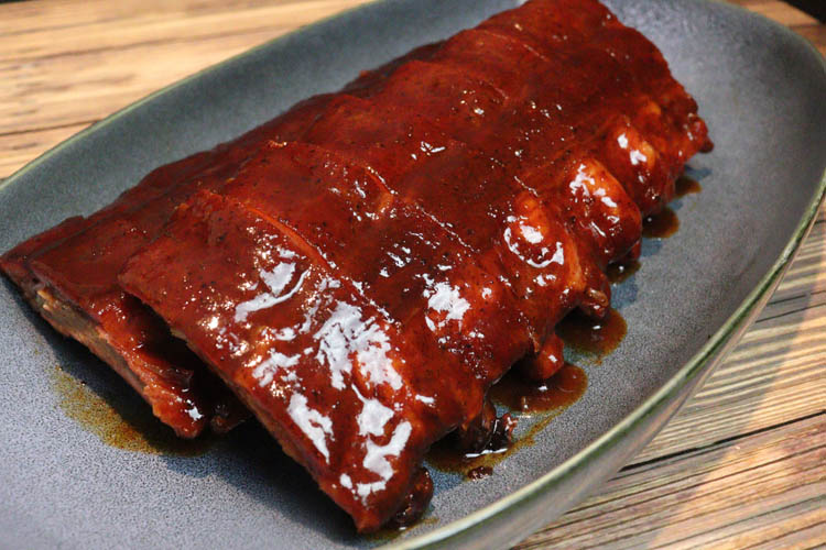 pork ribs basted with bbq sauce on a grey plate