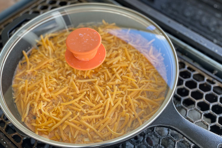 chicken dip in skillet with a lid sitting on grill