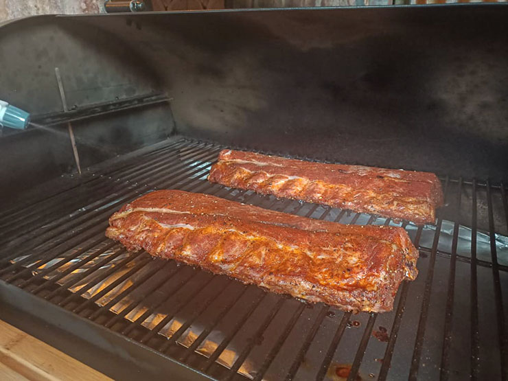 spritzing baby back ribs on a pellet grill