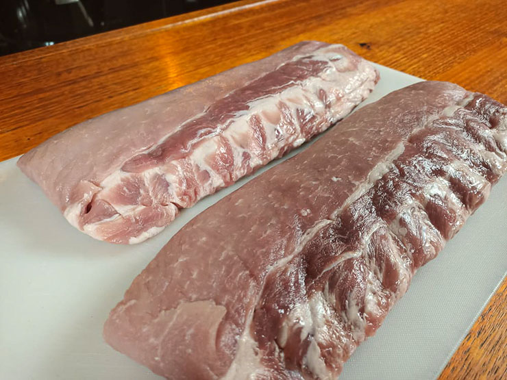 uncooked baby back pork ribs on a plastic board