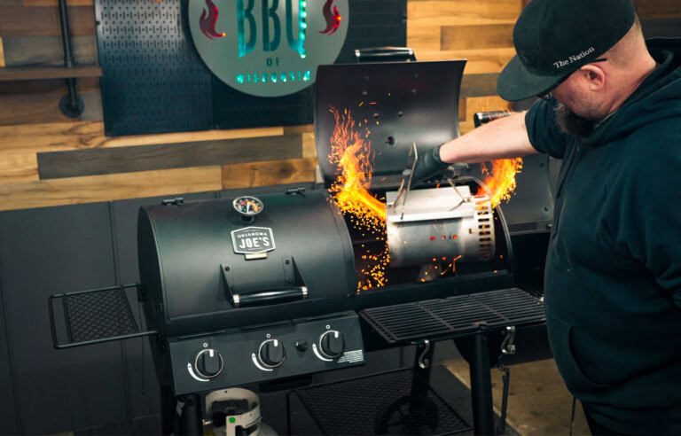 Man pouring lit charcoal from a chimney starter into the charcoal chamber of an Oklahoma Joe’s dual fuel gas and charcoal grill during testing.