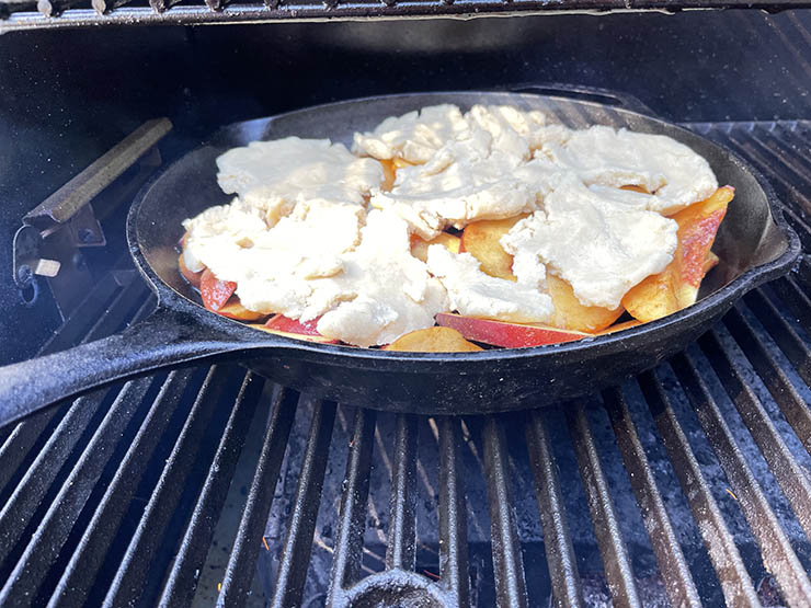 peach cobbler in a cast iron pan in a smoker