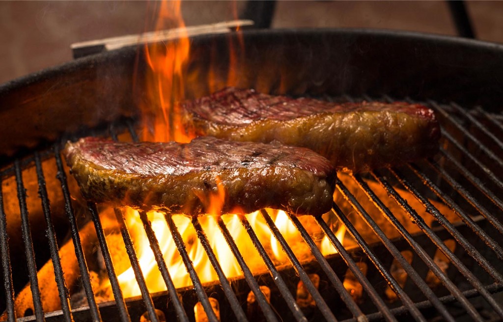 charcoal grill with fire touching steaks
