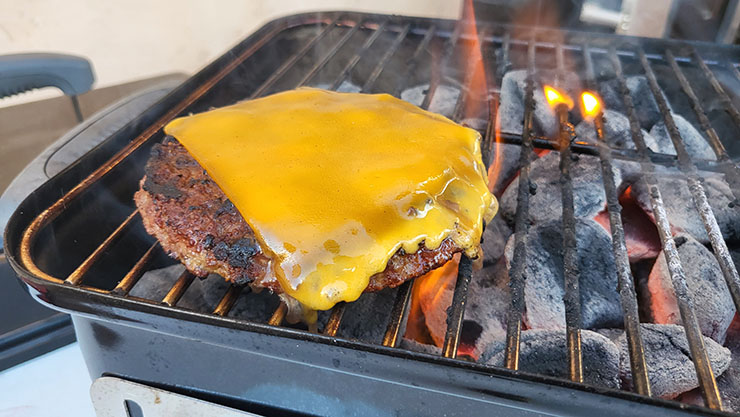 burger patty topped with cheese grilling on weber go-anywhere