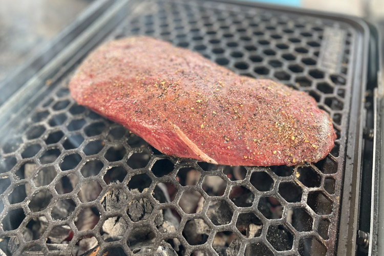 raw flat iron steak on the grill
