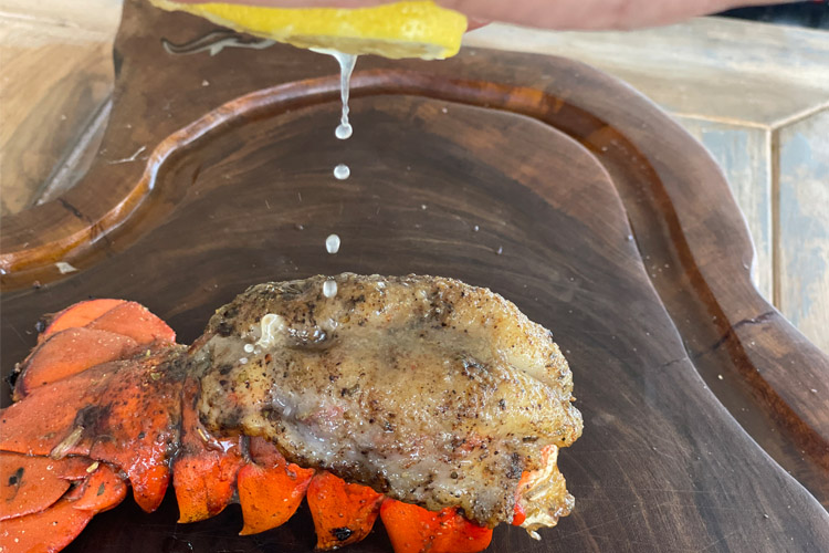 cooked lobster on wooden chopping board having lemon squeezed on it