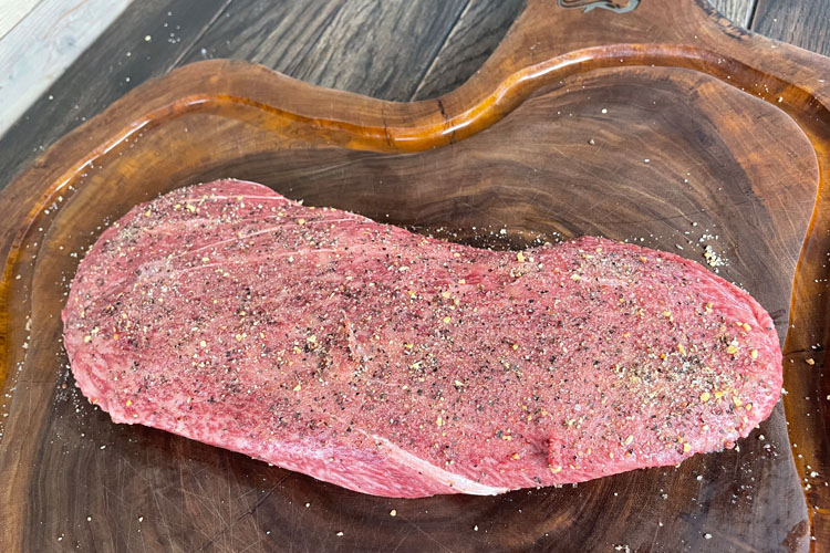 raw seasoned flat iron steak on chopping board