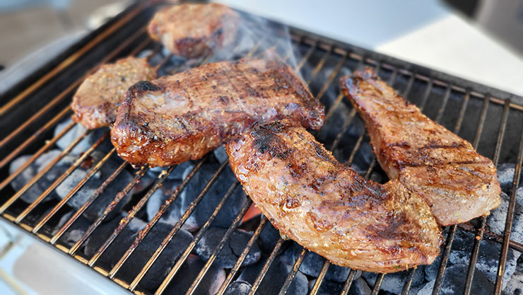 steaks grilling on weber go-anywhere