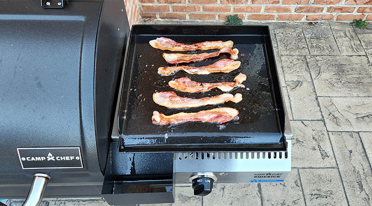 Camp Chef DLX 24 with attached sidekick system and frying bacon