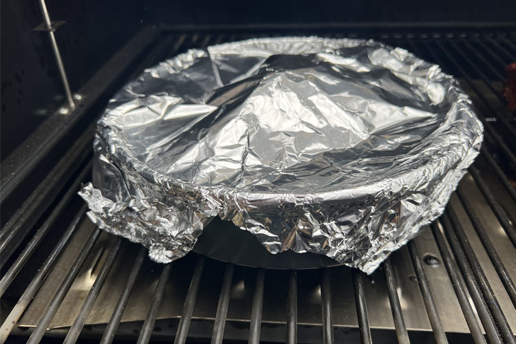 foil covered bowl sitting on smoker grill