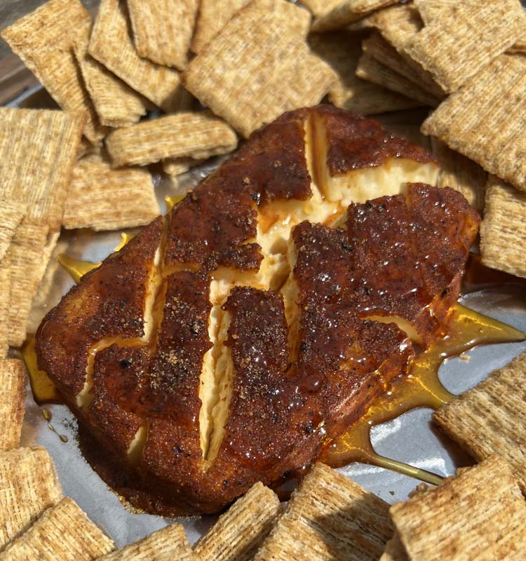hot honey cream cheese on a sliver tray with crackers around it