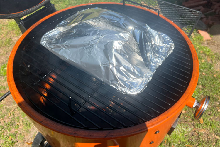 pork butt wrapped in foil sitting on smoker