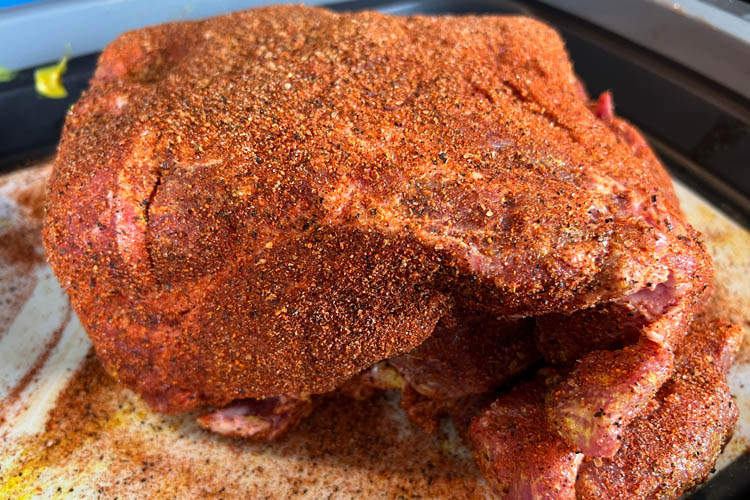 raw seasoned pork butt on a white tray