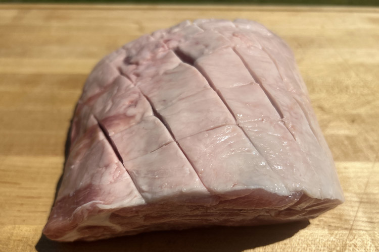 scored rack of pork on wooden board