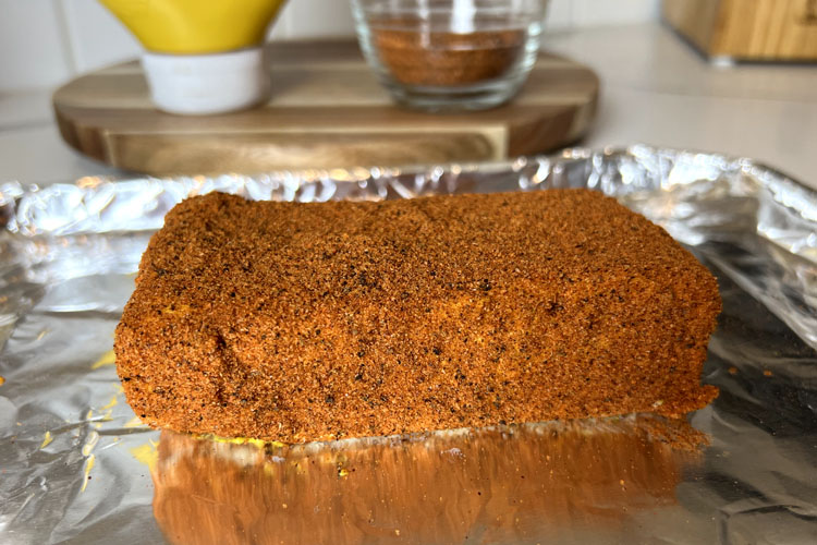 block of cream cheese covered in bbq rub on a silver tray