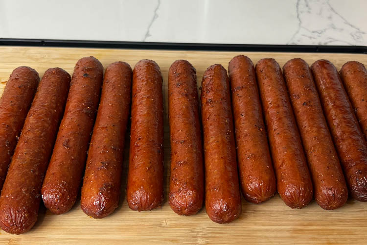 cooked franks on a wooden chopping board