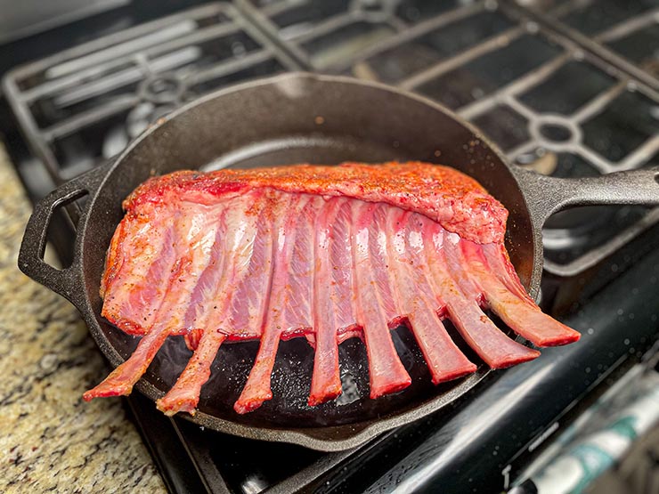 uncooked rack of lamb on cast iron pan