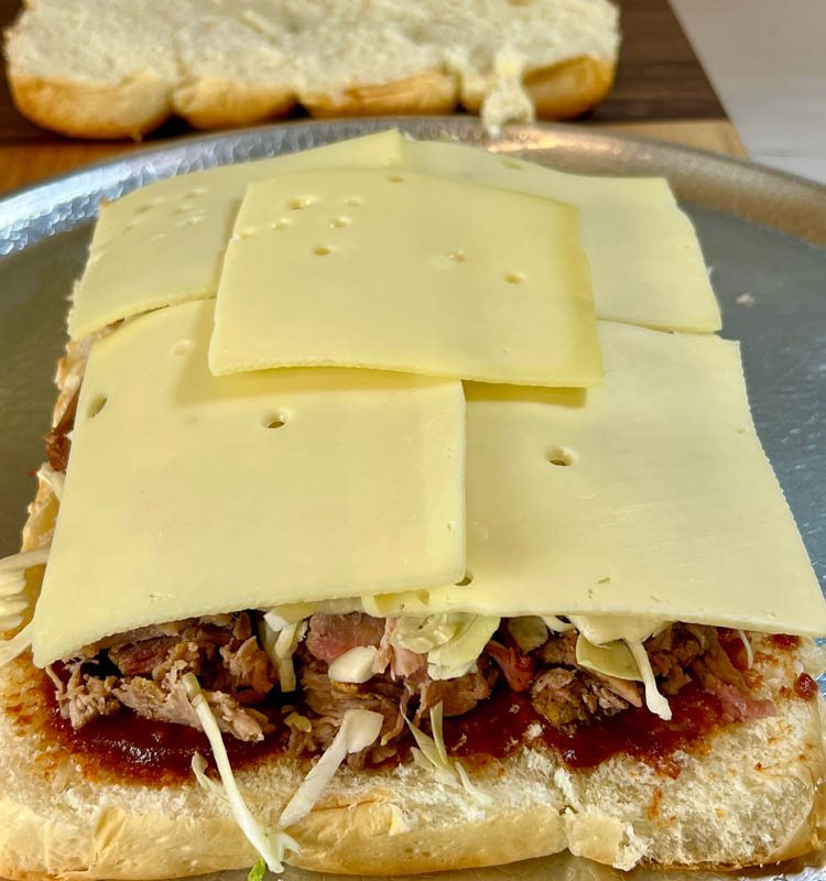 slab of slider buns with pork, cabbage and cheese slices on top