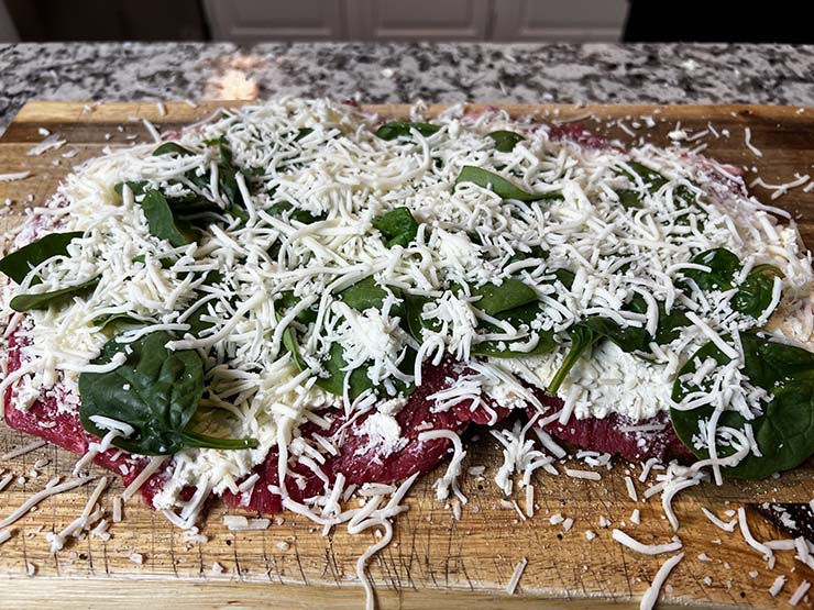 flattened flank steak with layers of cream cheese, spinach and mozzarella
