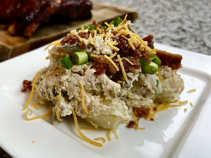 loaded potato salad with shredded cheddar cheese, onions and bacon