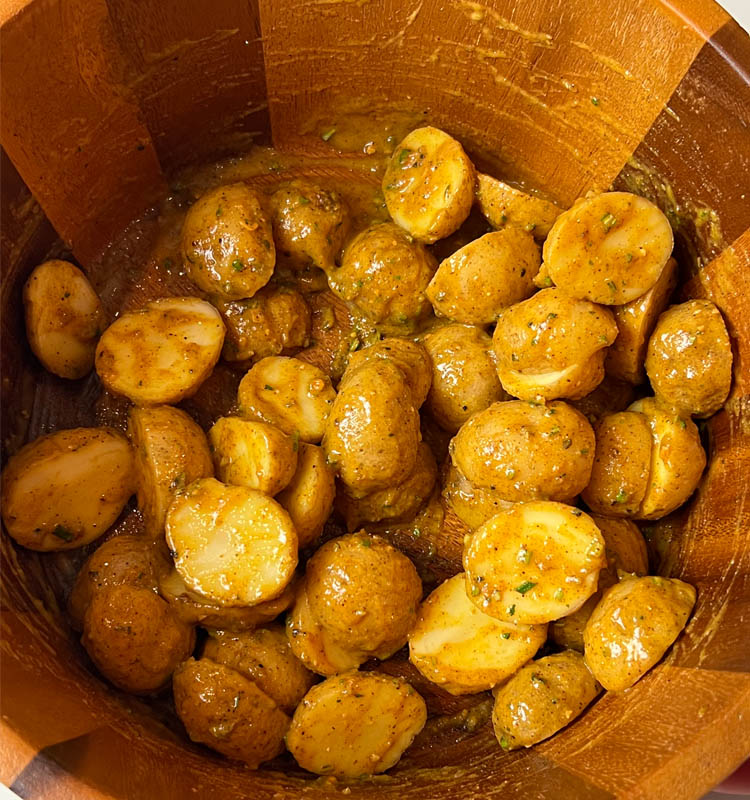 chopped raw potatoes in a mixing bowl covered in mustard