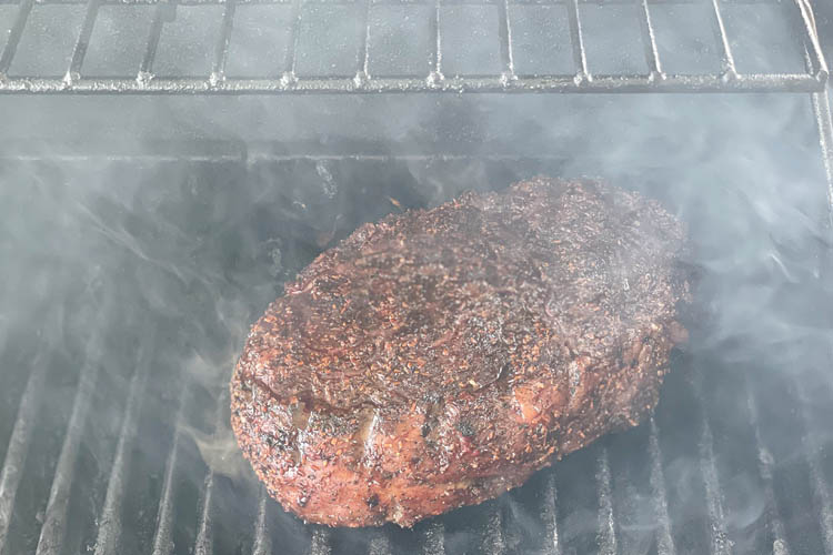 ribeye on the grill with smoke around it