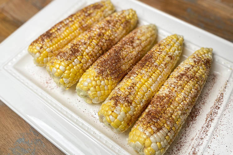 four seasoned corn on a white plate