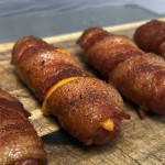 bacon wrapped cheese stuffed brats on serving board