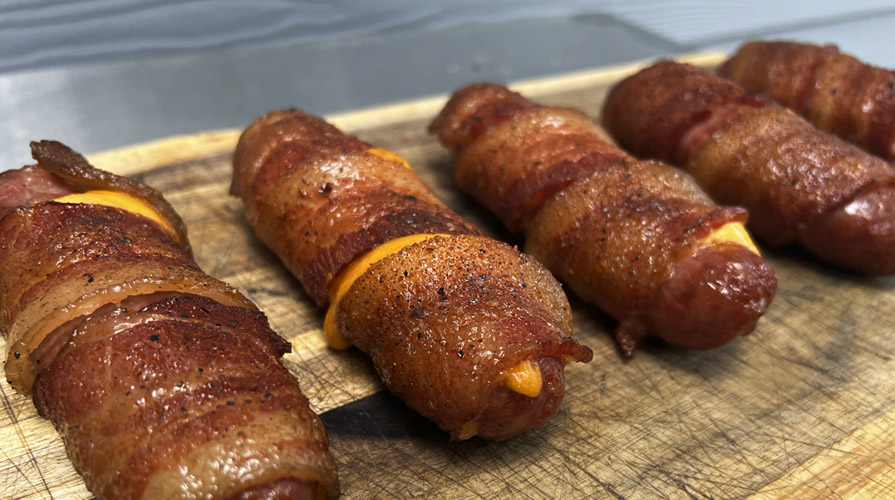bacon wrapped cheese stuffed brats on serving board