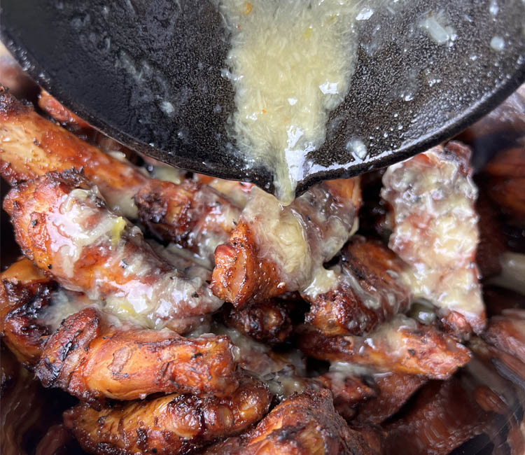 lemon sauce being poured on cooked wings