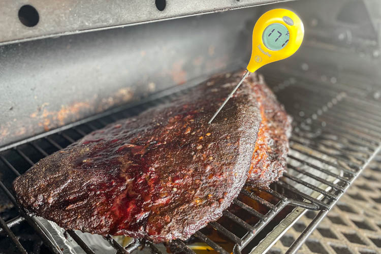 cooked brisket on grill with temperature probe in it reading 170°F