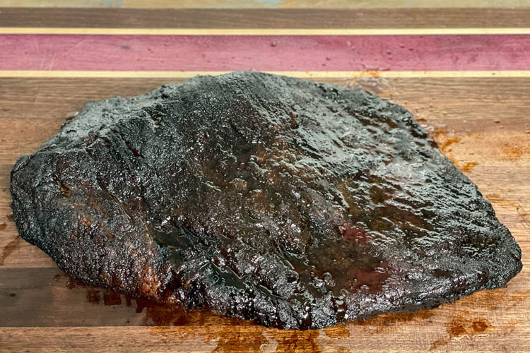 cooked brisket on wooden chopping board