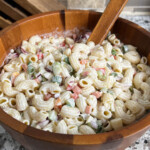 macaroni salad in a wooden bowl with a serving spooin in it