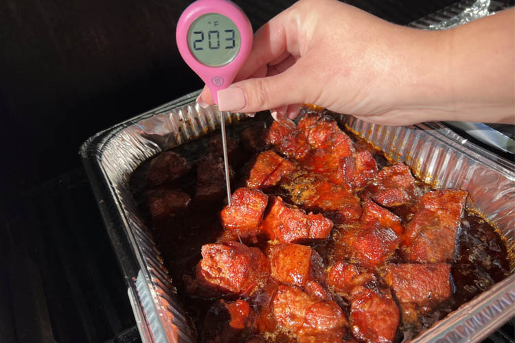 cooked pork butt cubes in foil tray with instant thermometer reading 203