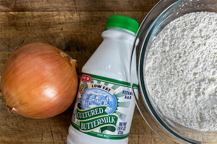 an onion, bottle of buttermilk and a bowl of flour
